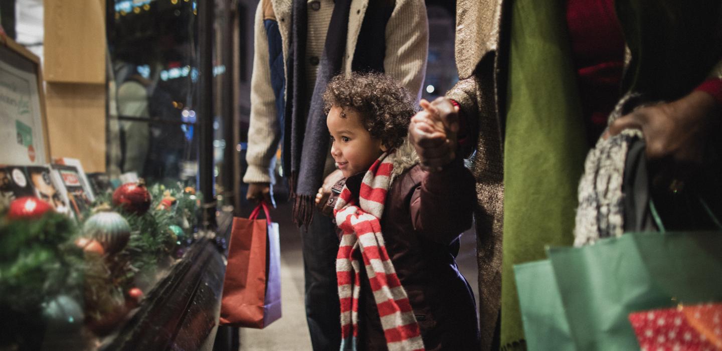 Child looks at holiday window display