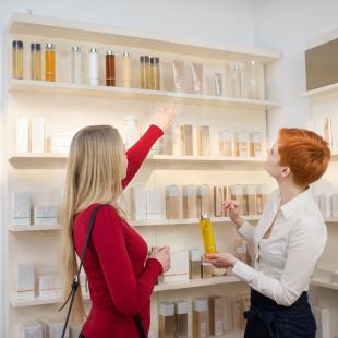 Two women are picking out colognes and perfumes at a makeup store