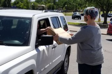 Store employee hands curbside pickup purchases through car window