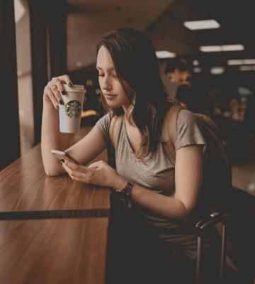 Woman on phone drinking Starbucks coffee at coffeeshop