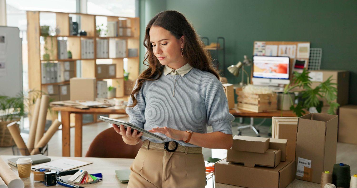 Woman works on tablet in an office with boxes