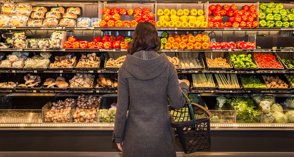 woman pondering choosing produce at a grocery store