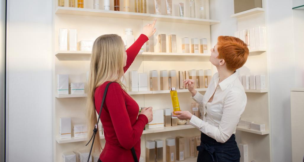 Two women are picking out colognes and perfumes at a makeup store