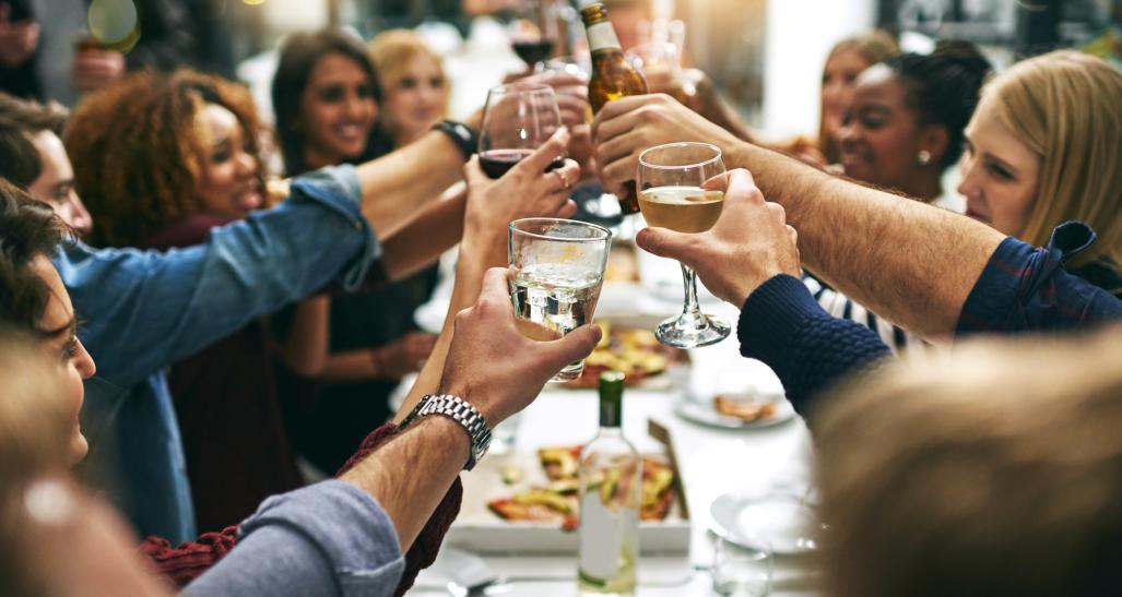 People cheer their wine glasses together at a restaurant over dinner