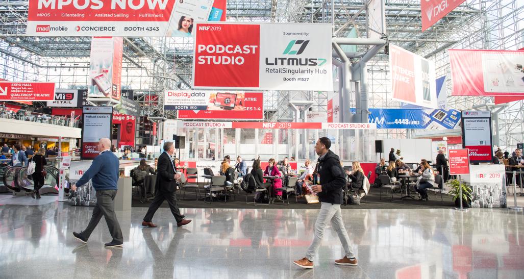 Conference attendees walk past banners at New York's Javits Center