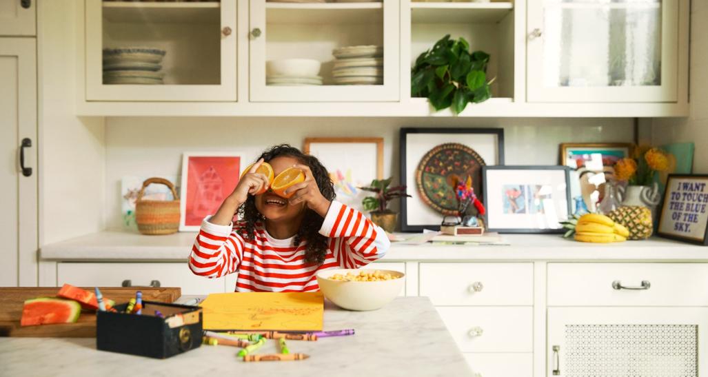 Girl in kitchen playing with oranges