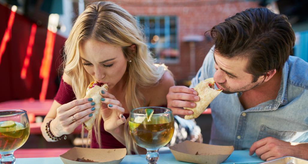 Two people eating tacos in an outdoor Mexican restaurant