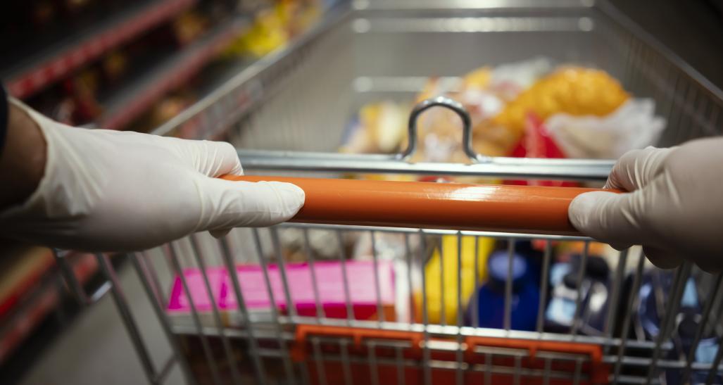 Woman wearing gloves pushes shopping cart