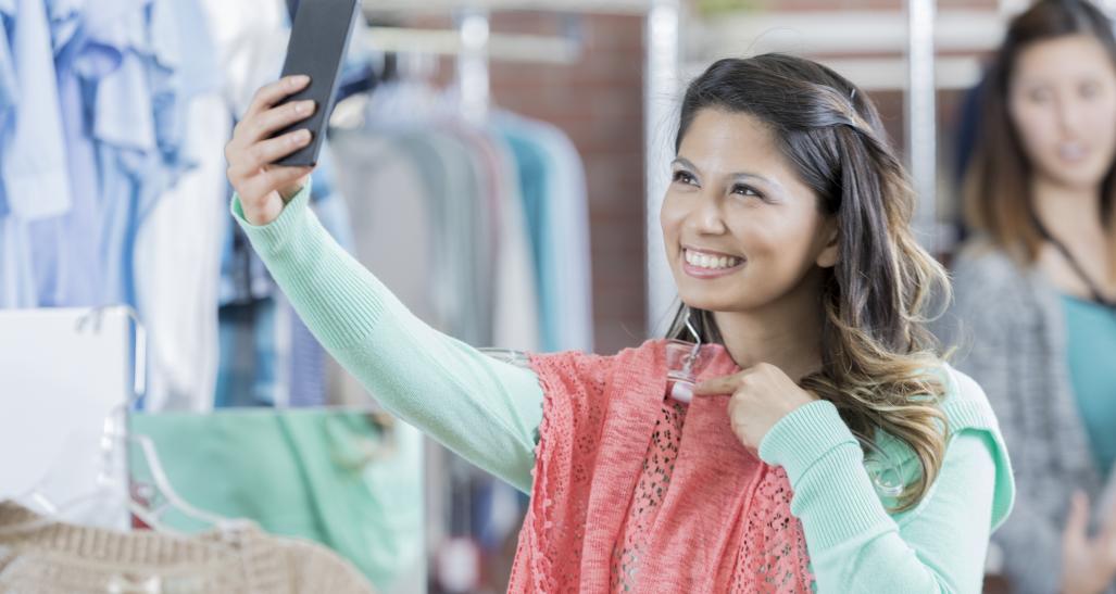 Woman takes a picture with her phone in a clothing store