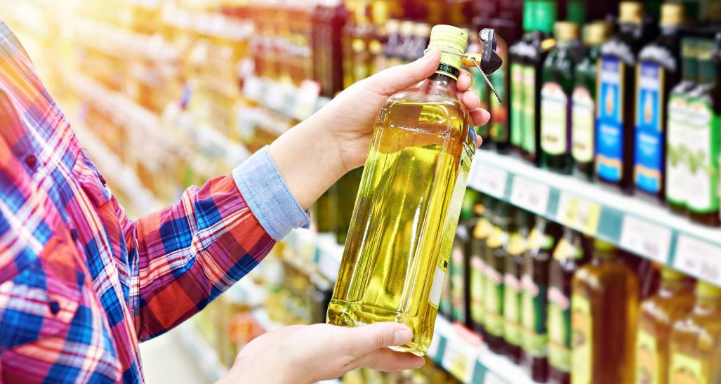 A woman holds cooking oil in grocery aisle