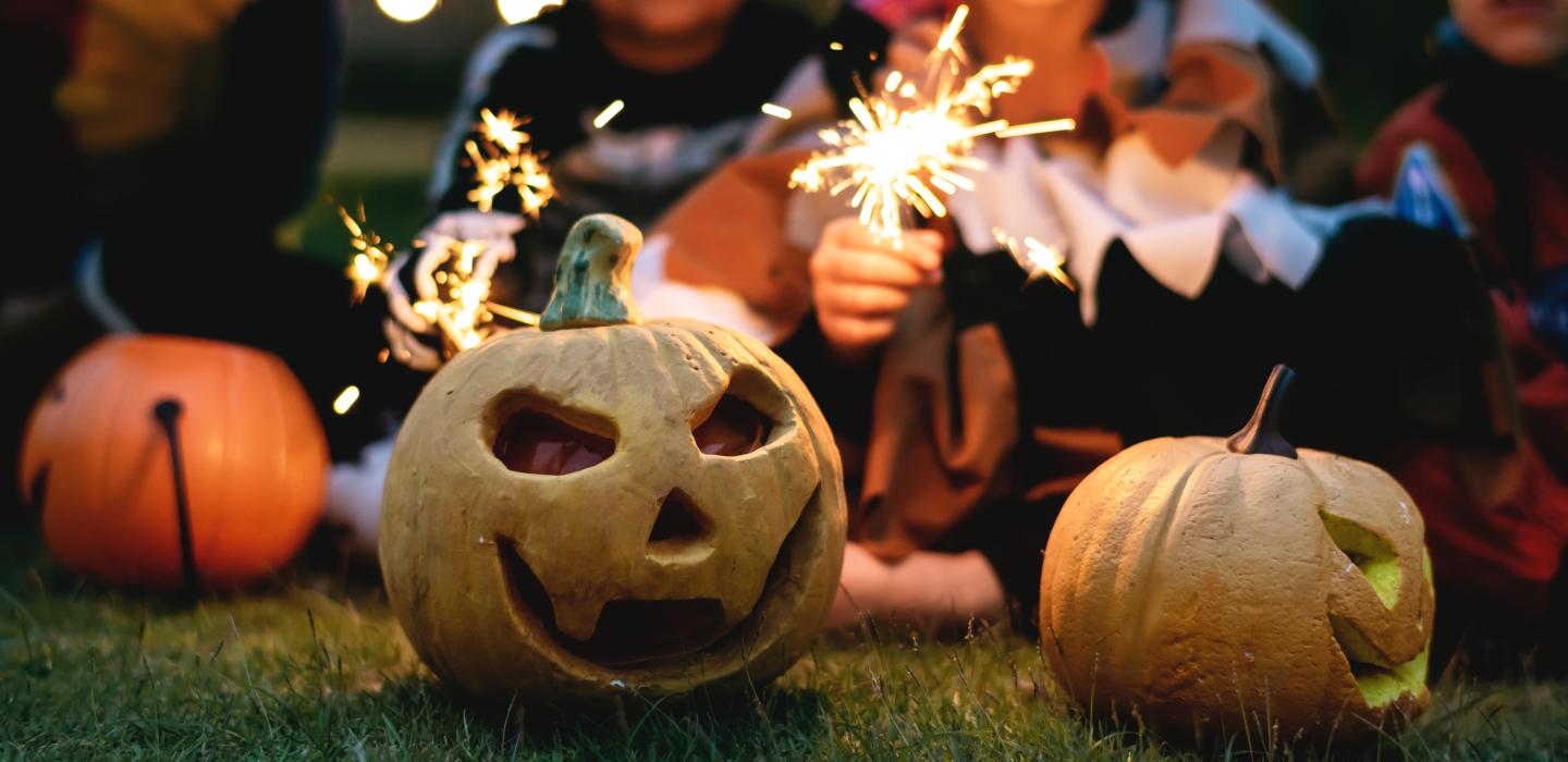 Kids with fireworks and Halloween carved pumpkins
