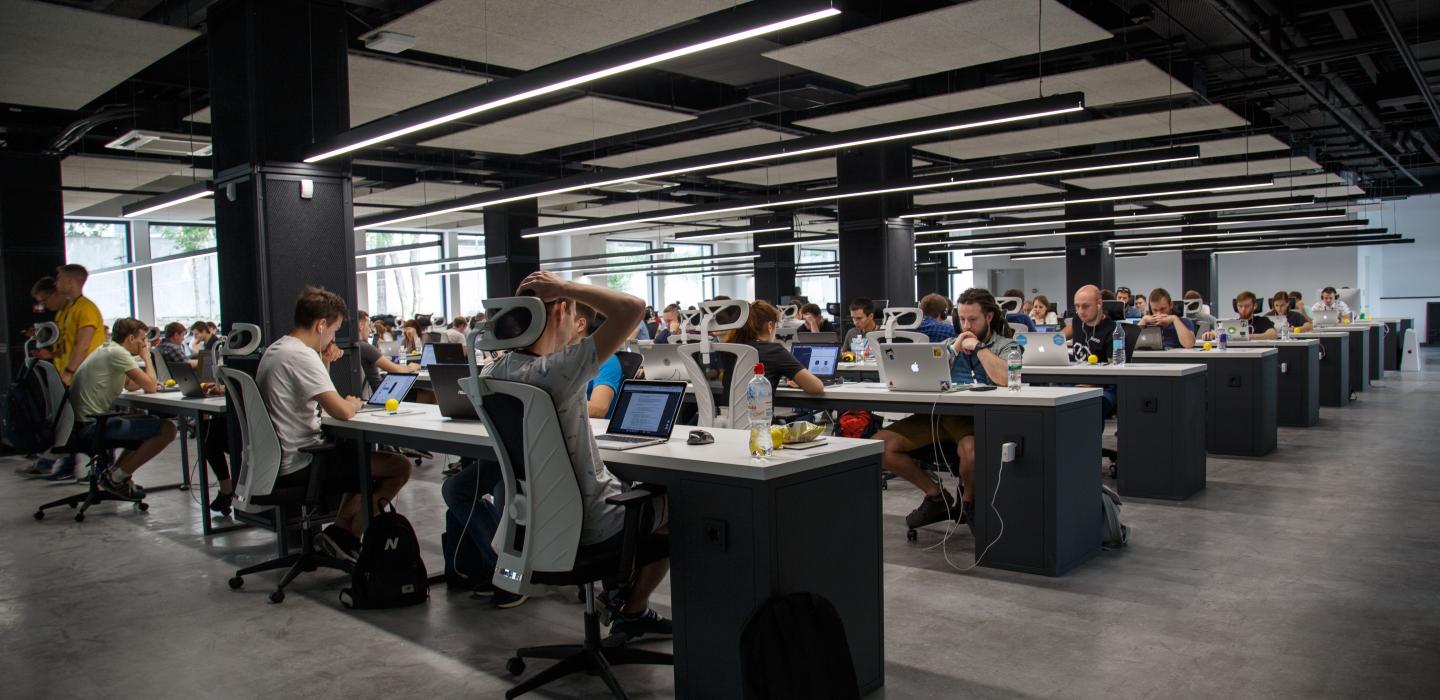 A collaborative workplace is shown with people working at their laptops