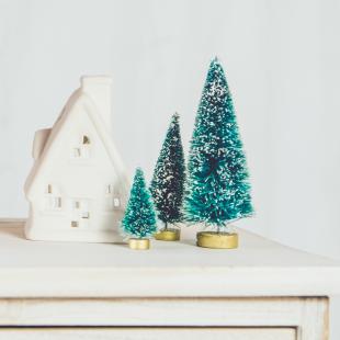 a house figurine and two small pine trees