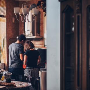 a man and a woman stand in the kitchen to prepare food