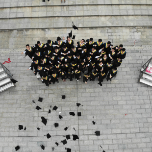 Group of kids stand outside in their cap and gowns after graduation