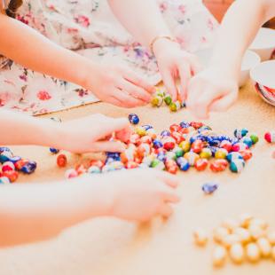 A group of children have their hands in easter candy on the floor