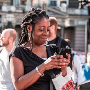 a woman looks down at her phone smiling