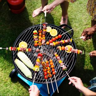 a grill showing people cooking skewers and other foods in the summer