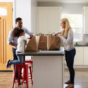 a family is shown in the kitchen after grocery shopping