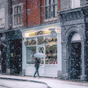 woman in a snowy town walking by stores