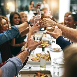 People cheer their wine glasses together at a restaurant over dinner