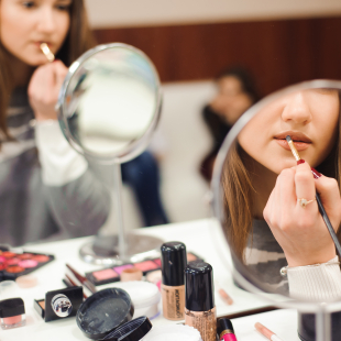 Putting on makeup looking at mirror