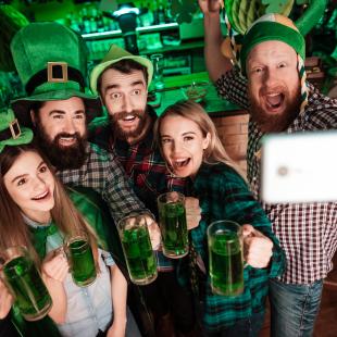 St. Patrick's Day group selfie at a bar with green beer