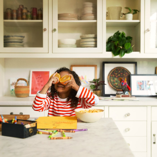 Girl in kitchen playing with oranges