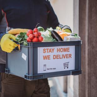 Man wearing gloves delivers box of produce