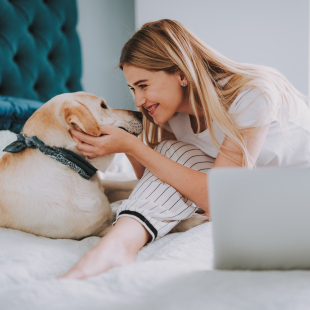 Woman petting dog in front of her laptop