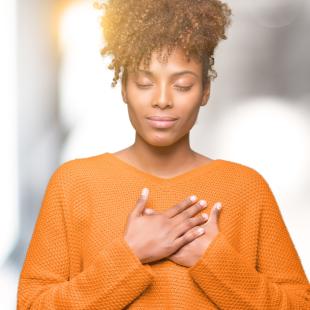 Woman with hands over heart and eyes closed