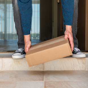 A man picks up a box on the doorstep