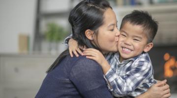 Mother kisses smiling young son