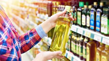 A woman holds cooking oil in grocery aisle
