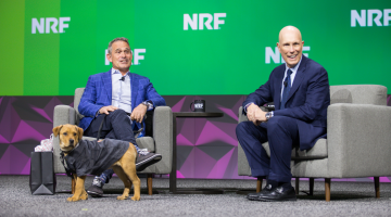 Petco CEO Ron Coughlin on the keynote stage at NRF 2023: Retail's Big Show with NRF's Matt Shay and a dog