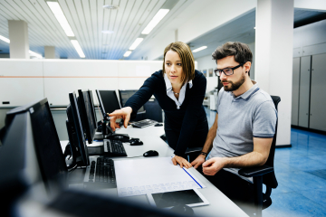 Professional woman pointing at computer for colleague