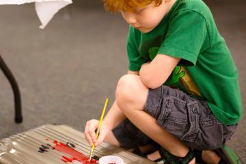 Child painting a suitcase from Unclaimed Baggage