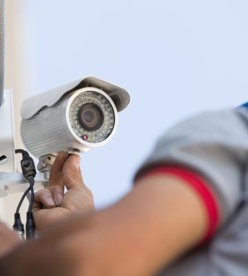 Man installing security camera on wall outside