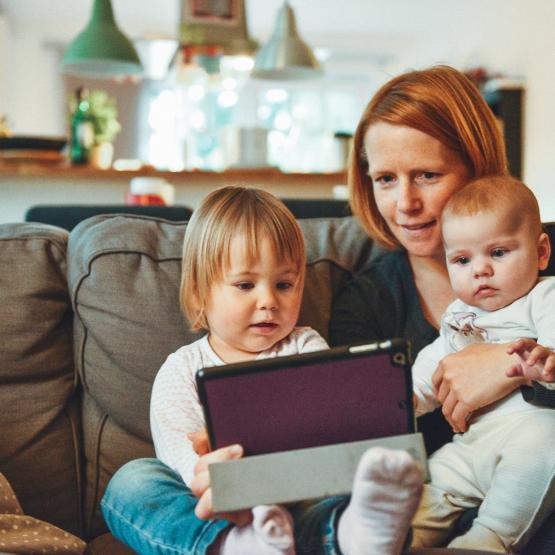 Mother with two kids on couch looking at tablet